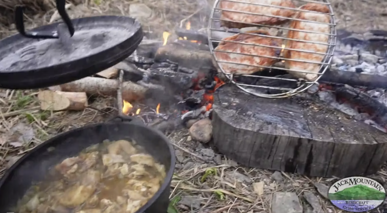 Image of two dutch ovens cooking on a campfire