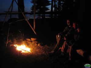 sitting by a campfire at dusk on a Maine lake