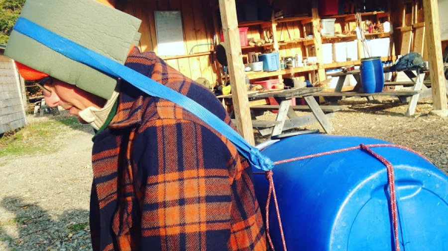 Improvised tumpline for a canoe barrel made from rope and nylon webbing