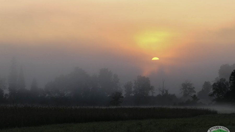 Sun Rising Behind The Ridge Over A Misty River