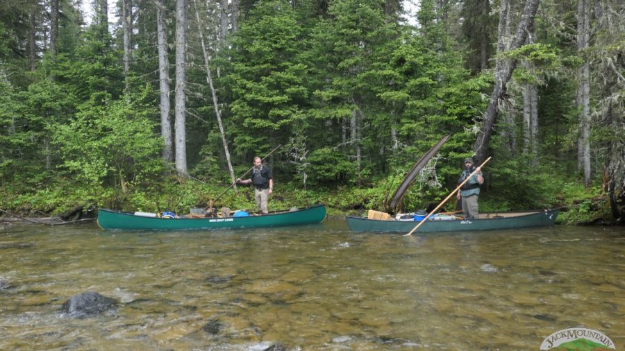 two people poling canoes on a remote river