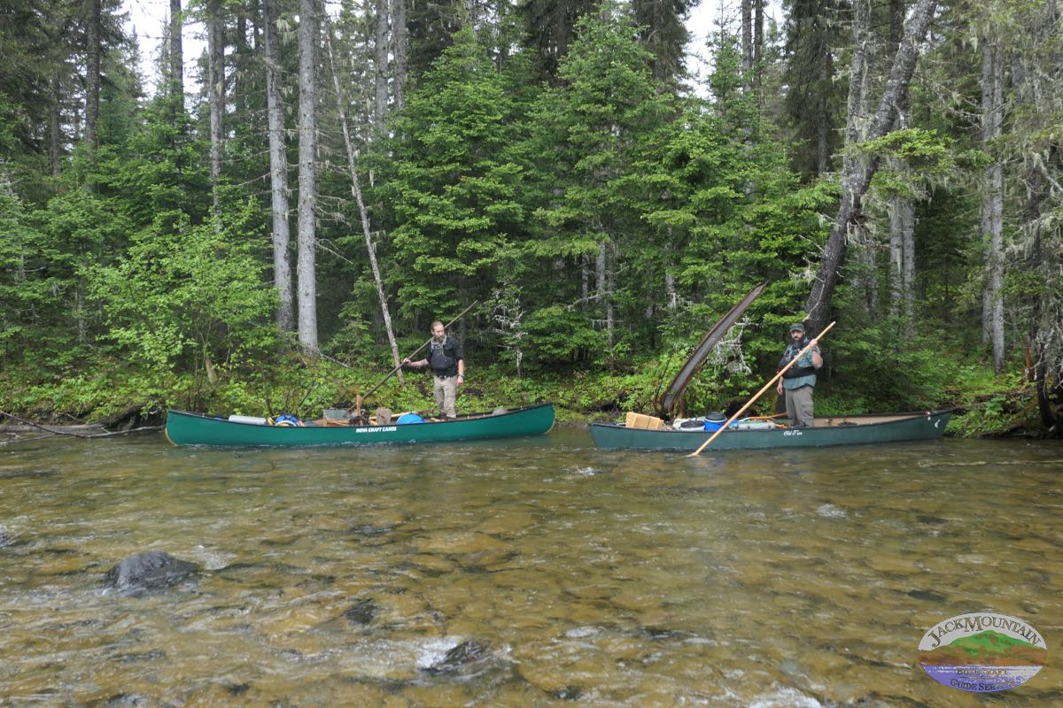 two people poling canoes on a remote river