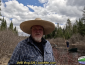 Tim standing by the stream with people poling canoes in the background