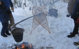 suspending a pot over a fire using snowshoes and a pole