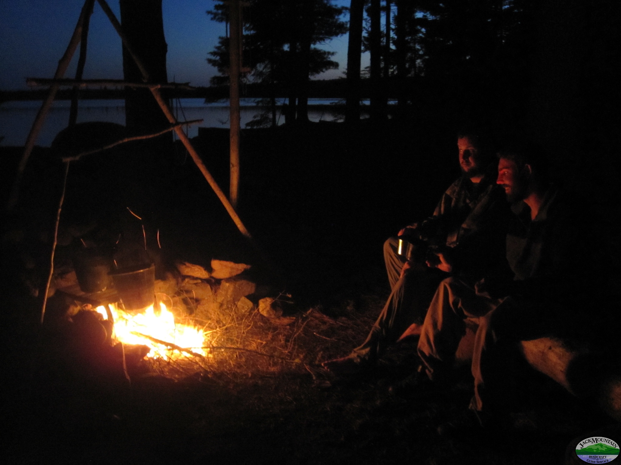 sitting by a campfire at dusk on a Maine lake